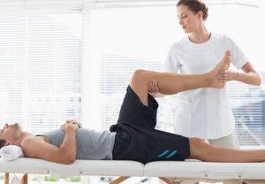 Physiotherapist massaging leg of man