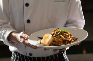 Spaghetti, a chef uniform holding a dish of seafood spaghetti